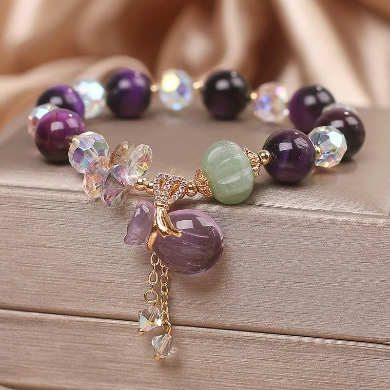 Women's crystal bracelet with purple Tigereye money bag pendant and clear rhinestone accents