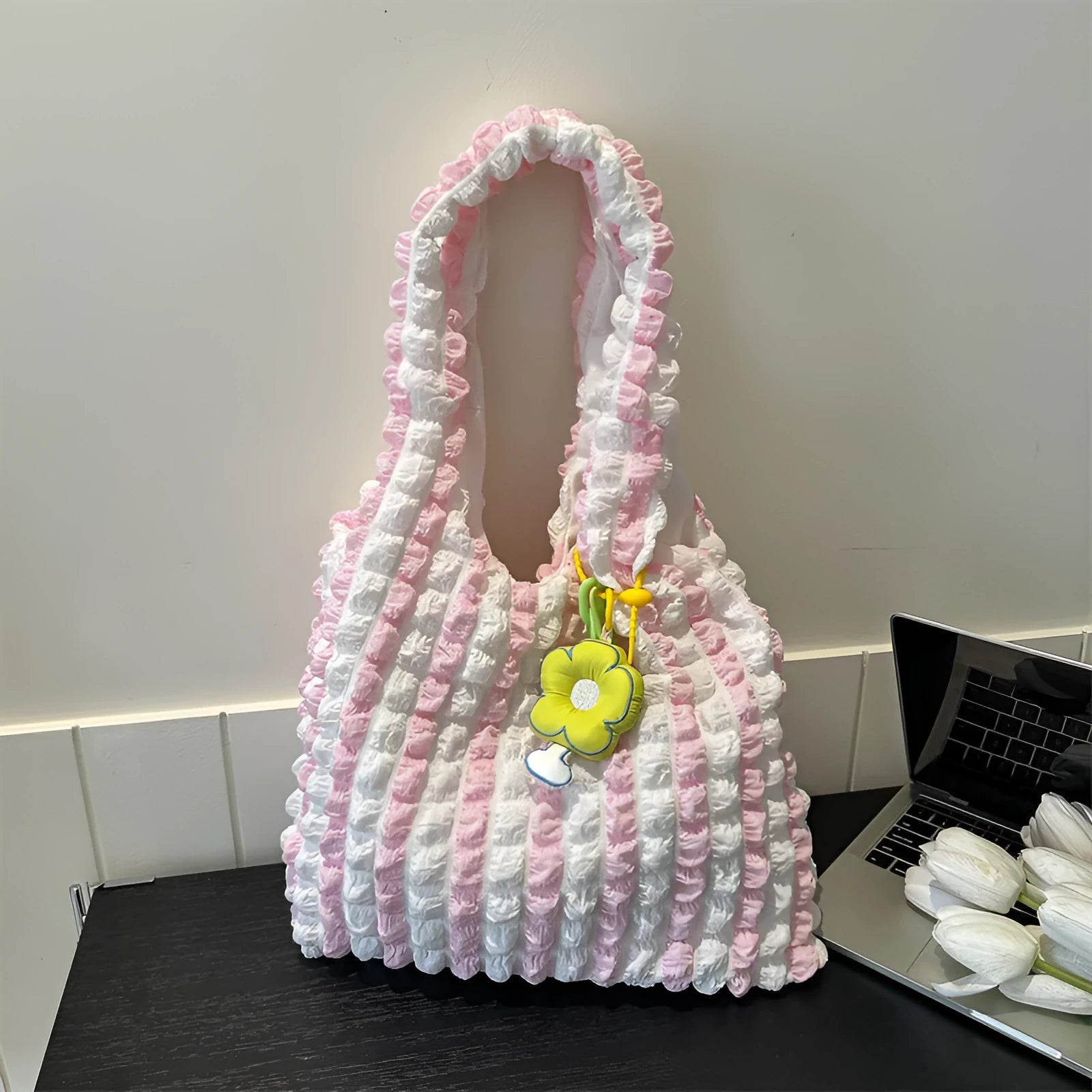 Pleated bubble bag in beige polyester with fold detailing, pendant, and cross-body strap