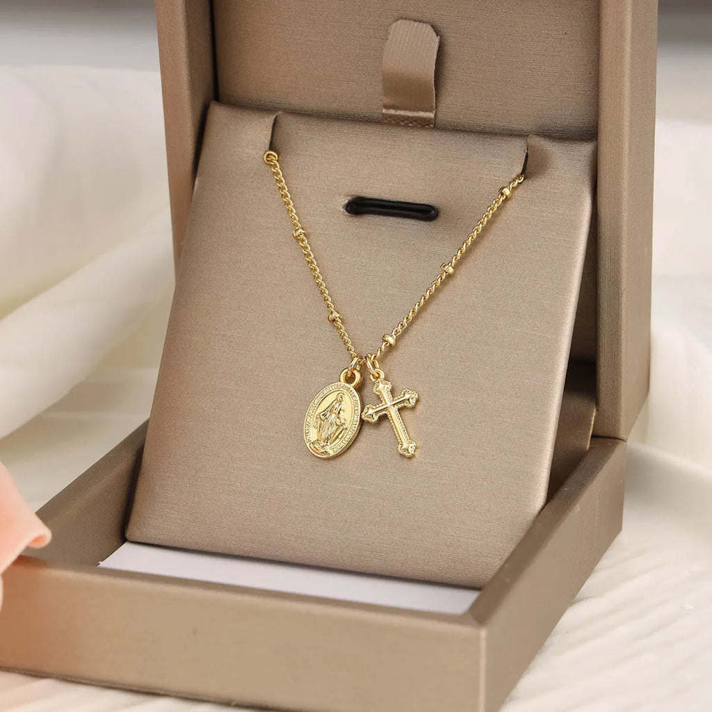 Gold geometric cross necklace with Virgin Mary ornament on a simple chain.