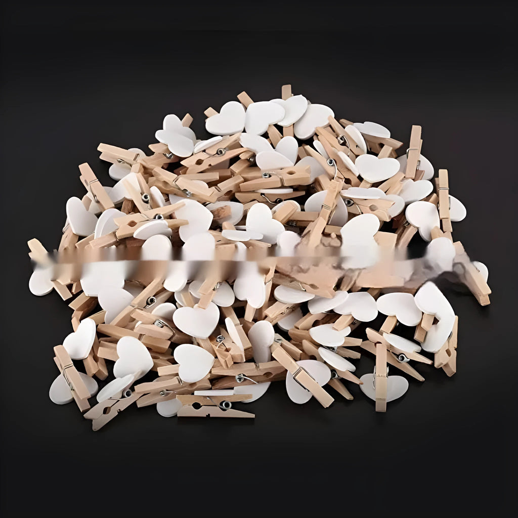 Five wooden heart-shaped clips in different colours on wooden surface