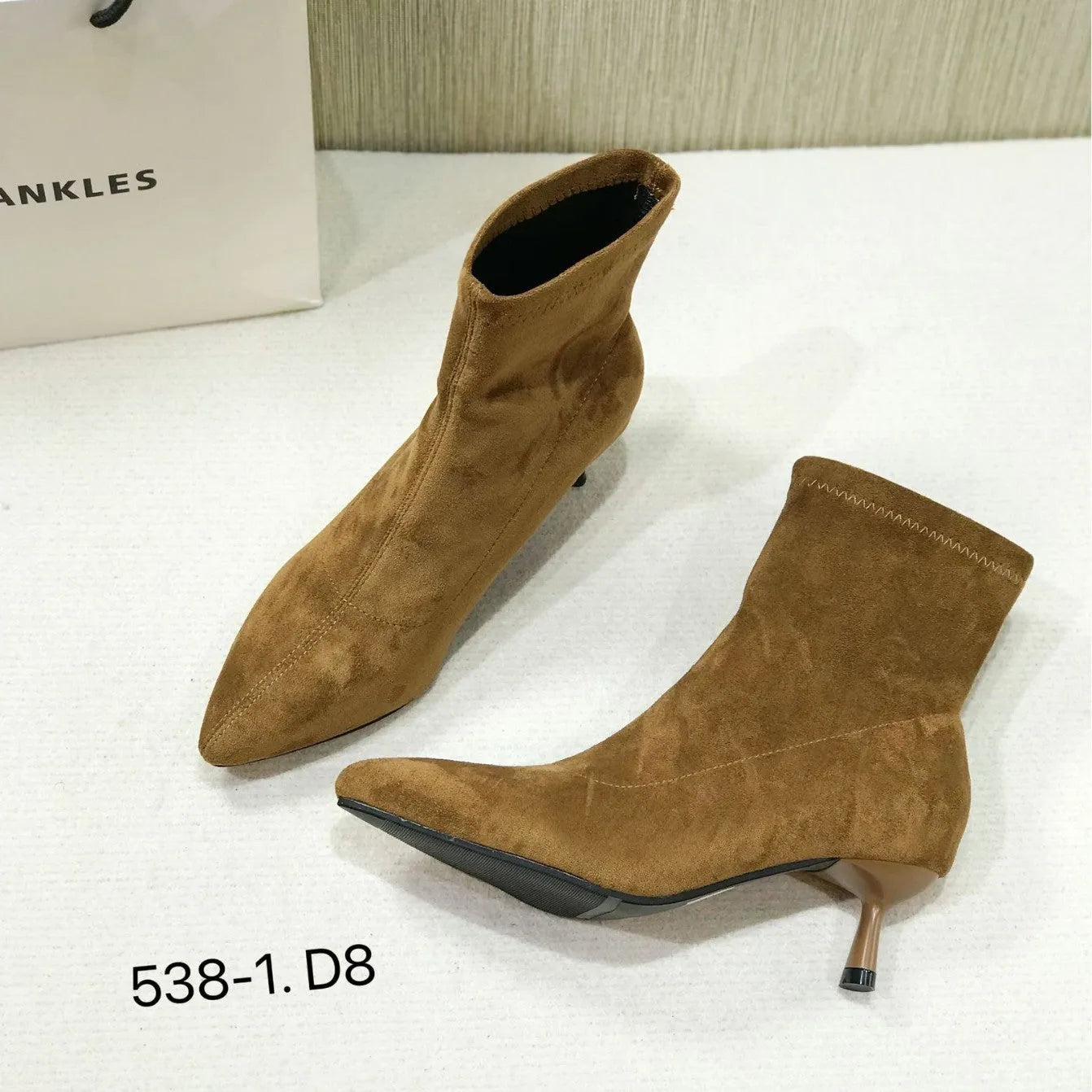 Black pointed toe ankle boots with a stiletto heel on a white background