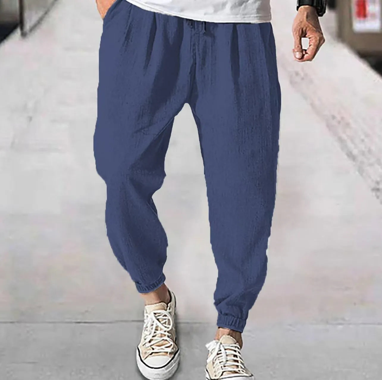 Men's loose cotton ankle banded trousers in khaki colour on a hanger.