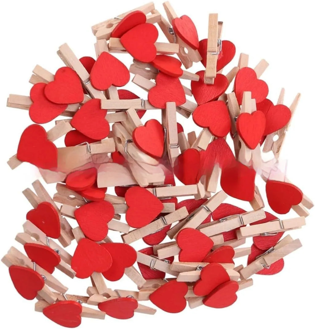 Five wooden heart-shaped clips in different colours on wooden surface