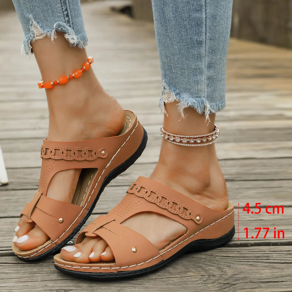 Pair of beige Roman style slippers with a fish mouth toe and slope heel on a rubber sole.