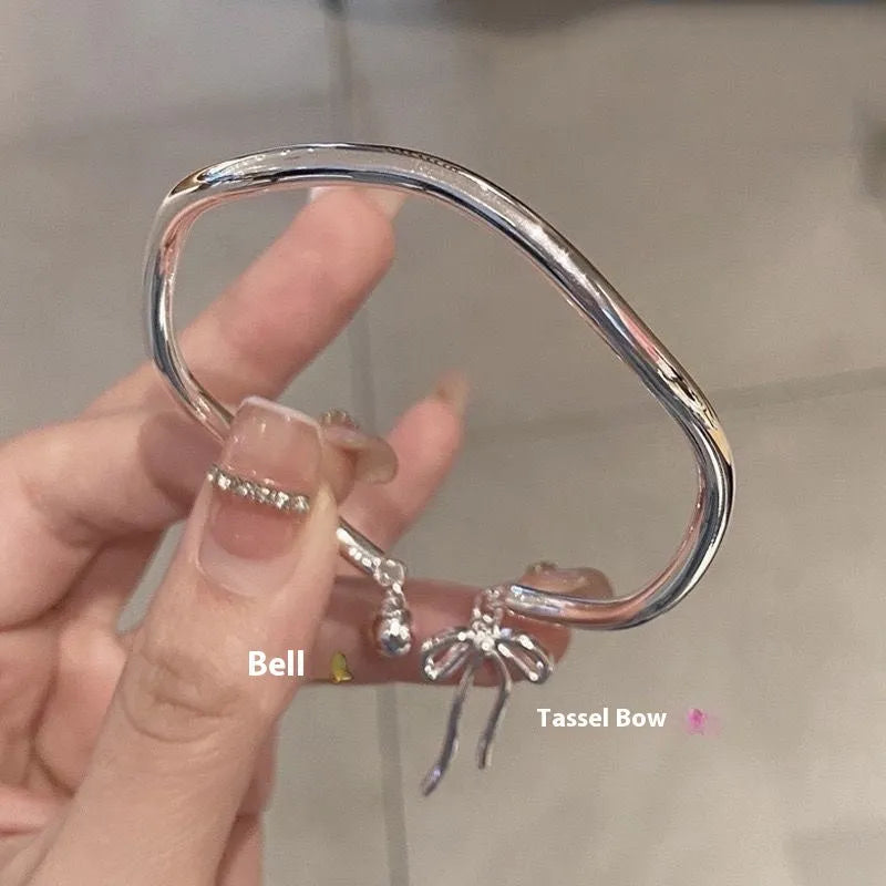 Silver adjustable bracelet with bow charm and small bell detail on wrist