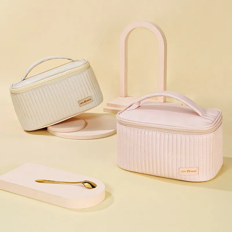 Open-top cake style makeup bag in PU leather shown in a light colour, with cosmetics inside.