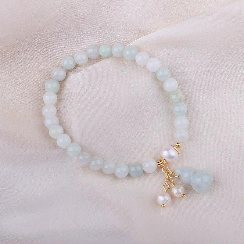 Close-up of a Chinese style jade bracelet for women featuring a natural emerald jade gourd charm on a band.