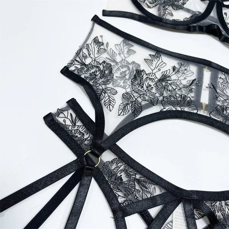 Black women's lace mesh floral print three-piece set with top, trousers, and waist ring on a hanger.