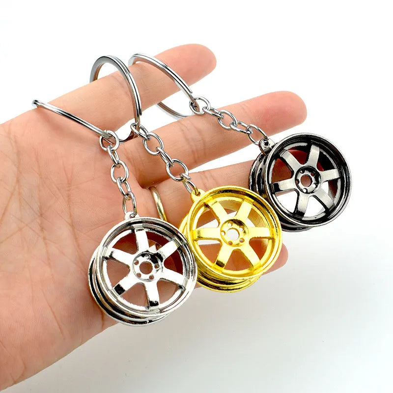 Zinc alloy car wheel hub keychain in gold finish with detailed hub pattern on white background