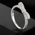 Silver bow-shaped crystal ring with zircon rhinestones on a finger.