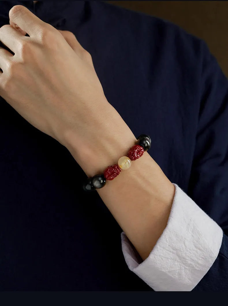 Natural cinnabar bead bracelet with carved animal zodiac design in gold obsidian and silver stone on a silver gift box