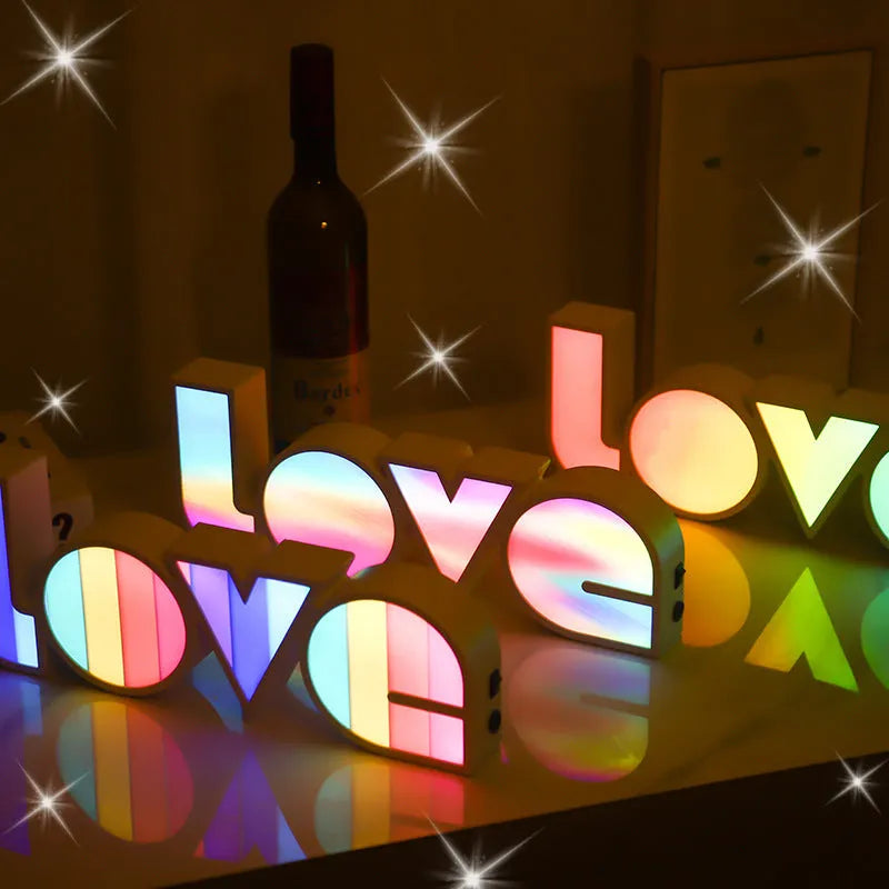 LED LOVE light with rainbow lampshade on a table against a dark background