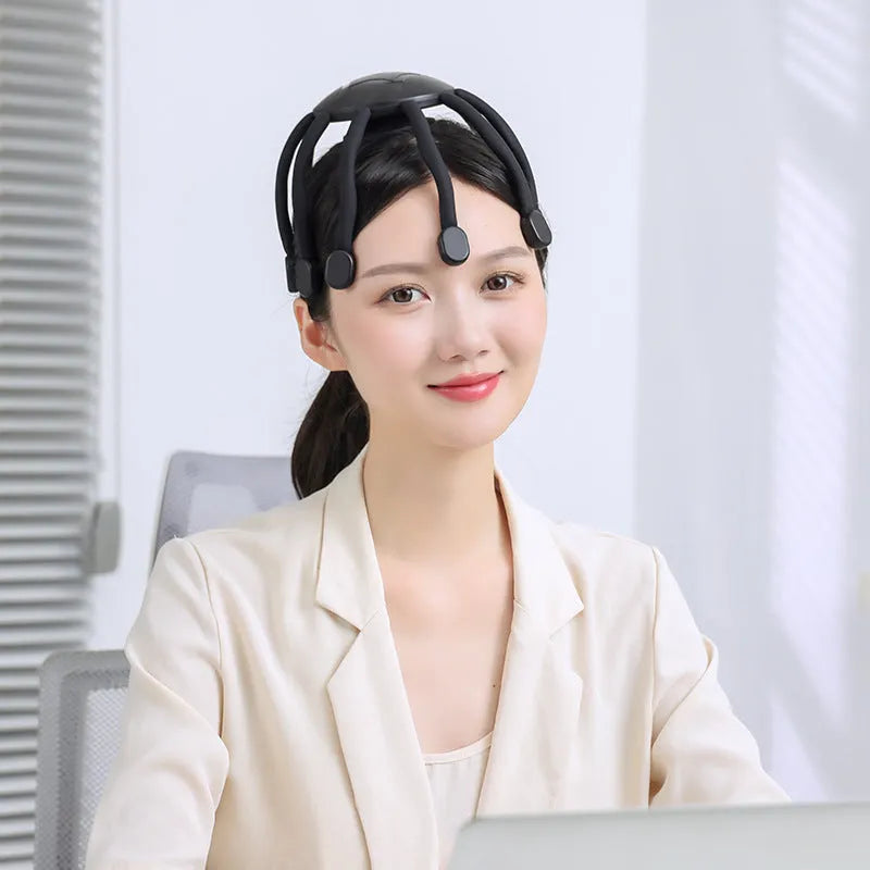 Black handheld electric scalp massager with multiple flexible silicone claws vibrating on a scalp.