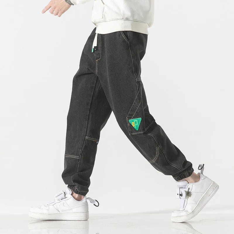 Men's loose-fit tapered cotton trousers in grey shown flat, with mid waist and tapered leg detail.