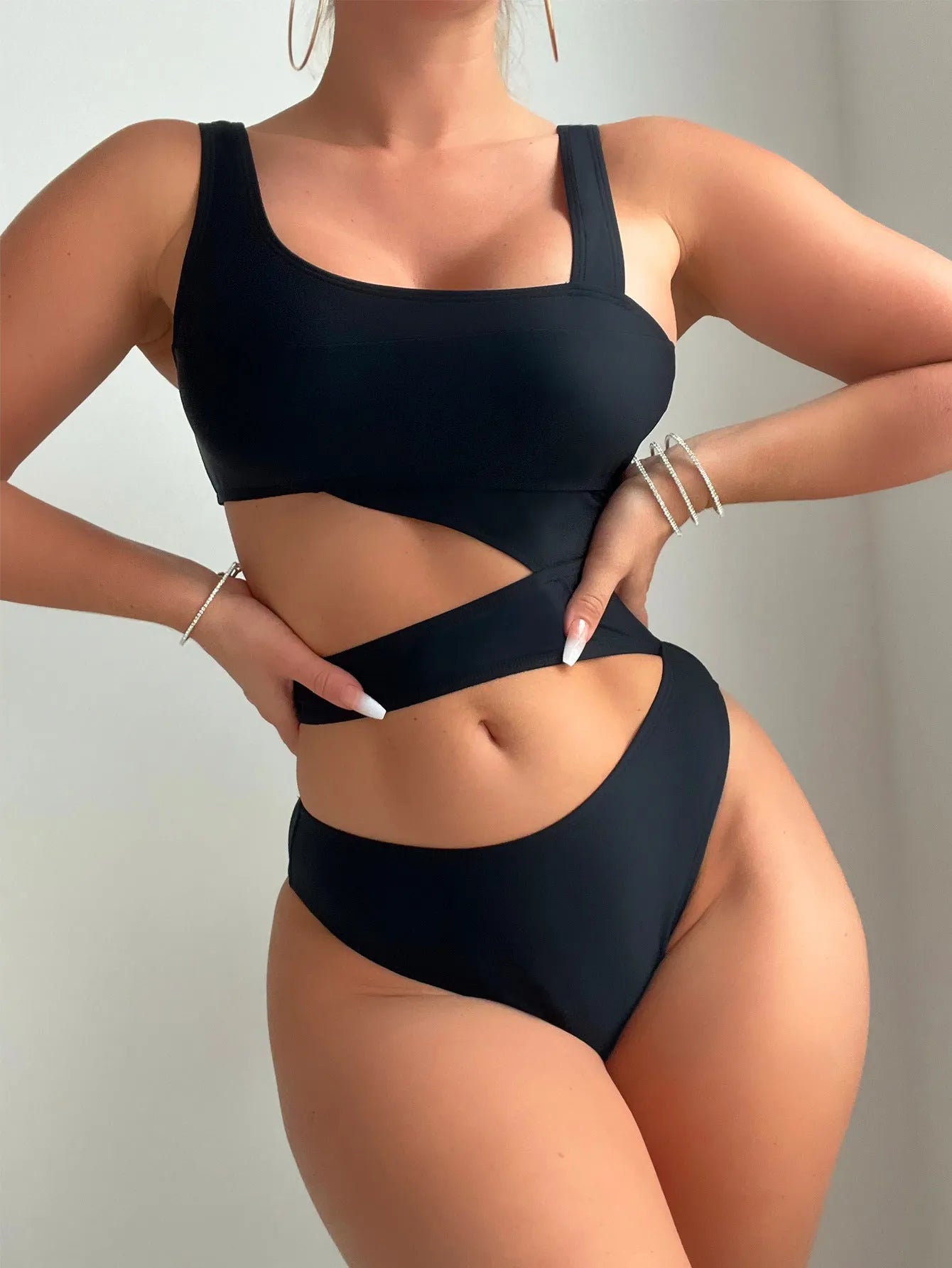 Women's solid black one-piece swimsuit with hollow cut-out design and high-cut leg on display