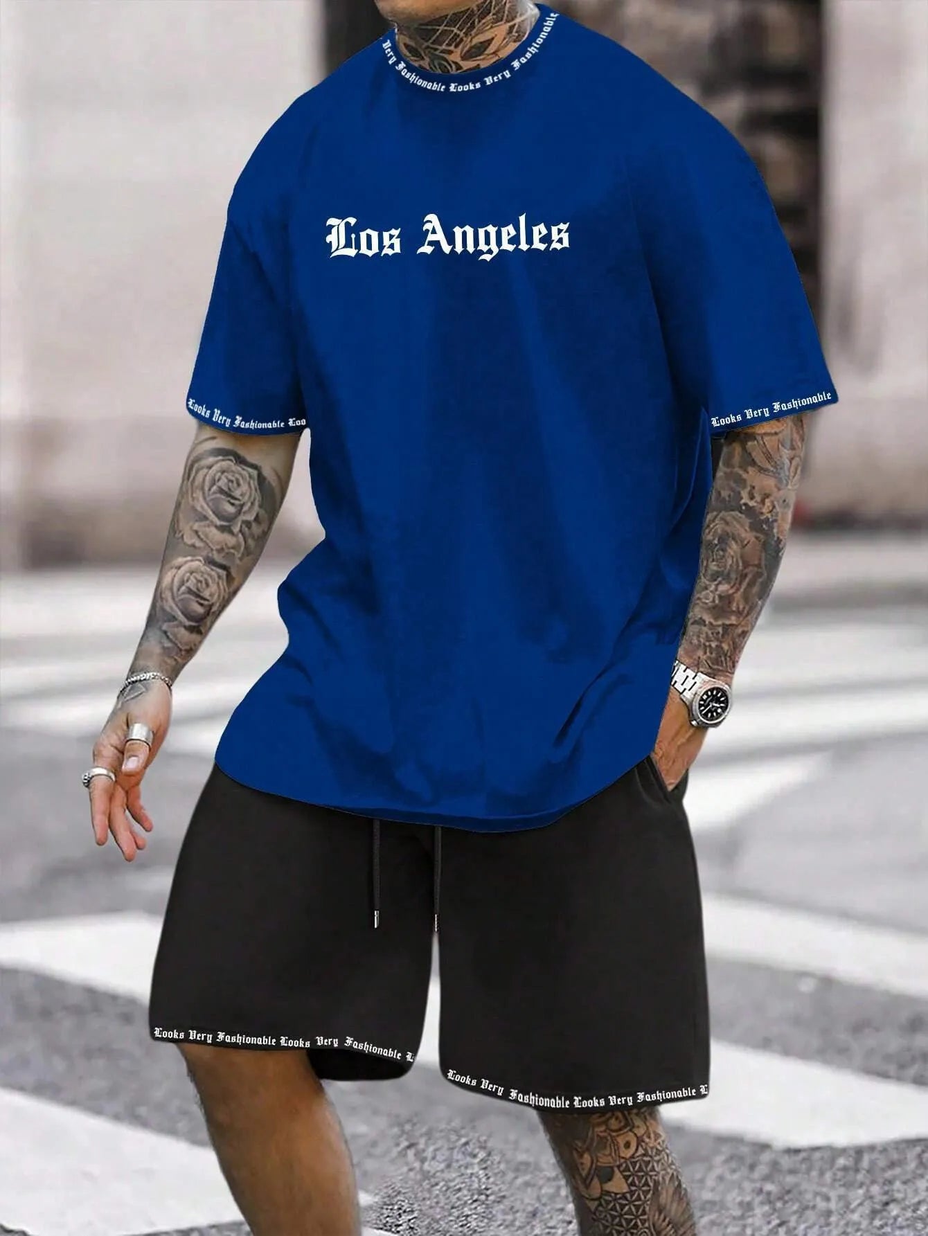 Man wearing a blue printed short-sleeved top and matching shorts from a sports-style two-piece set.