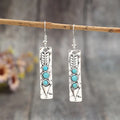 Long strip geometric silver earrings with inlaid turquoise detail on a white background