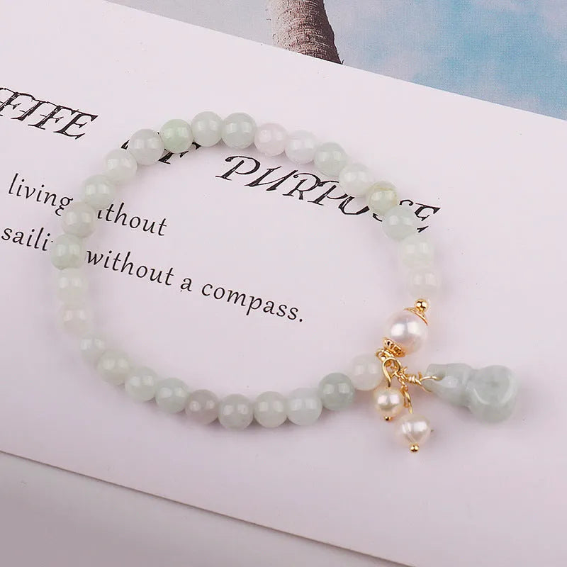 Close-up of a Chinese style jade bracelet for women featuring a natural emerald jade gourd charm on a band.