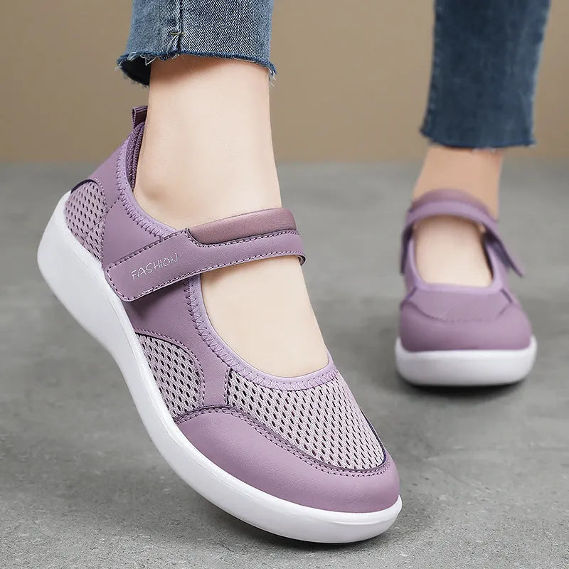 Women's grey low-top cloth shoes with mesh upper and Velcro strap on a flat sole.