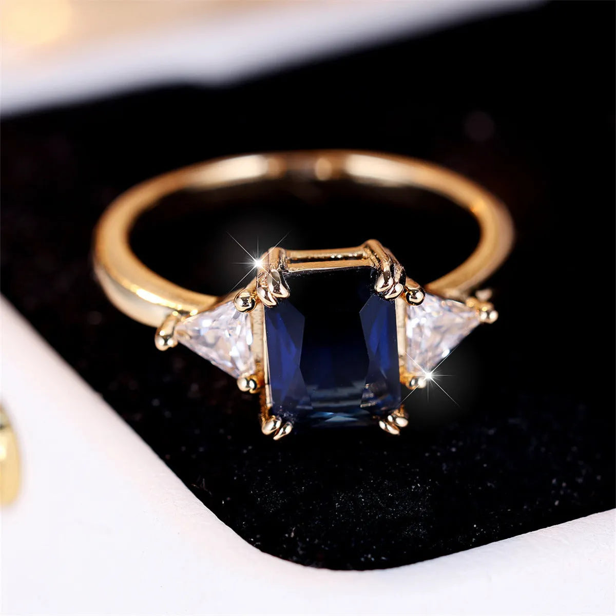 Gold sapphire blue rectangular copper ring for women on plain background
