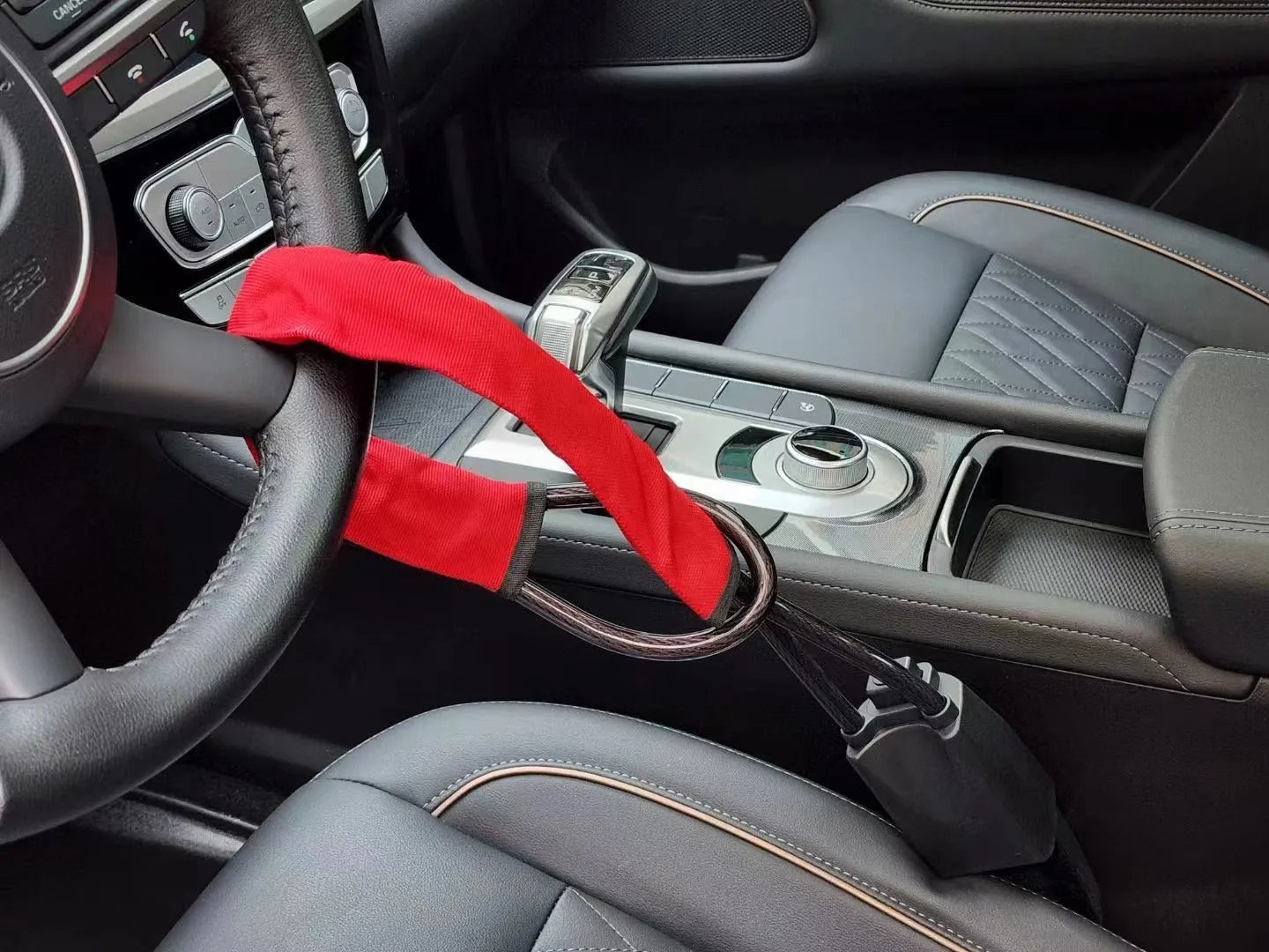 Red iron car steering wheel lock with copper core on a car steering wheel.