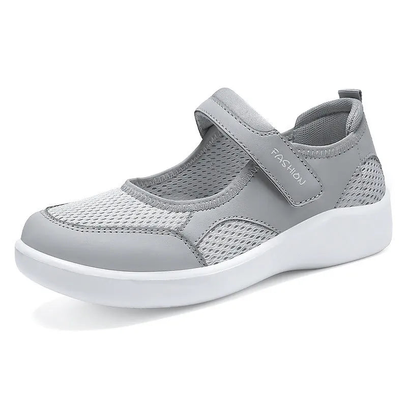 Women's grey low-top cloth shoes with mesh upper and Velcro strap on a flat sole.