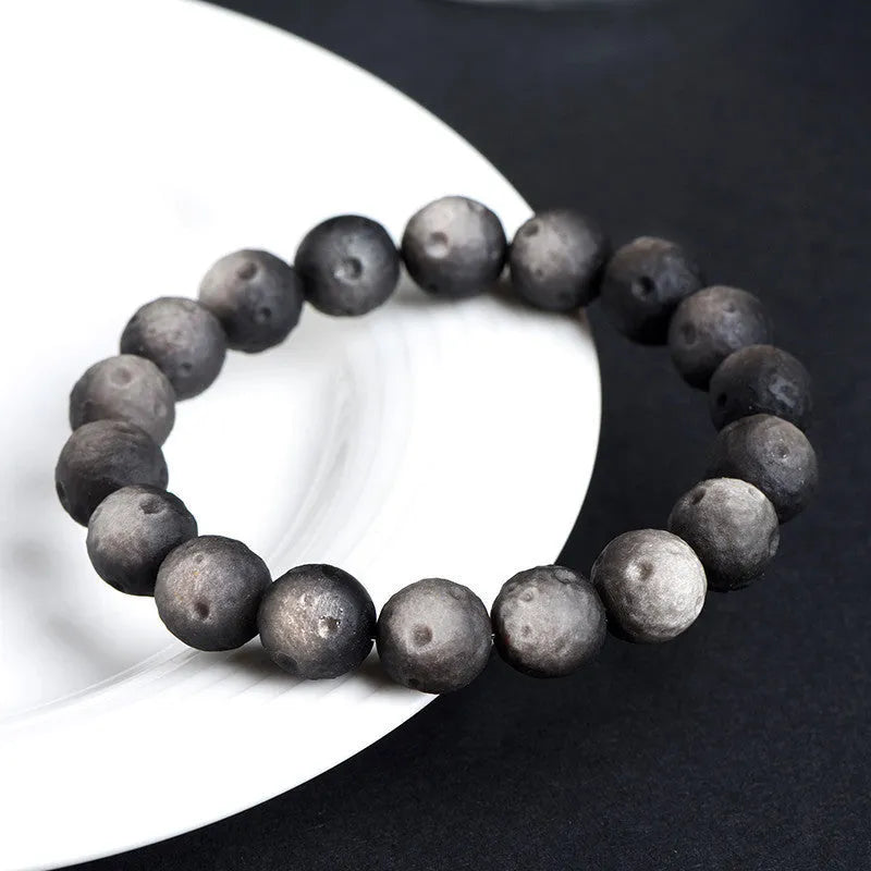 Natural obsidian crater ball bracelet in gold or silver meteorite finish on a wrist.