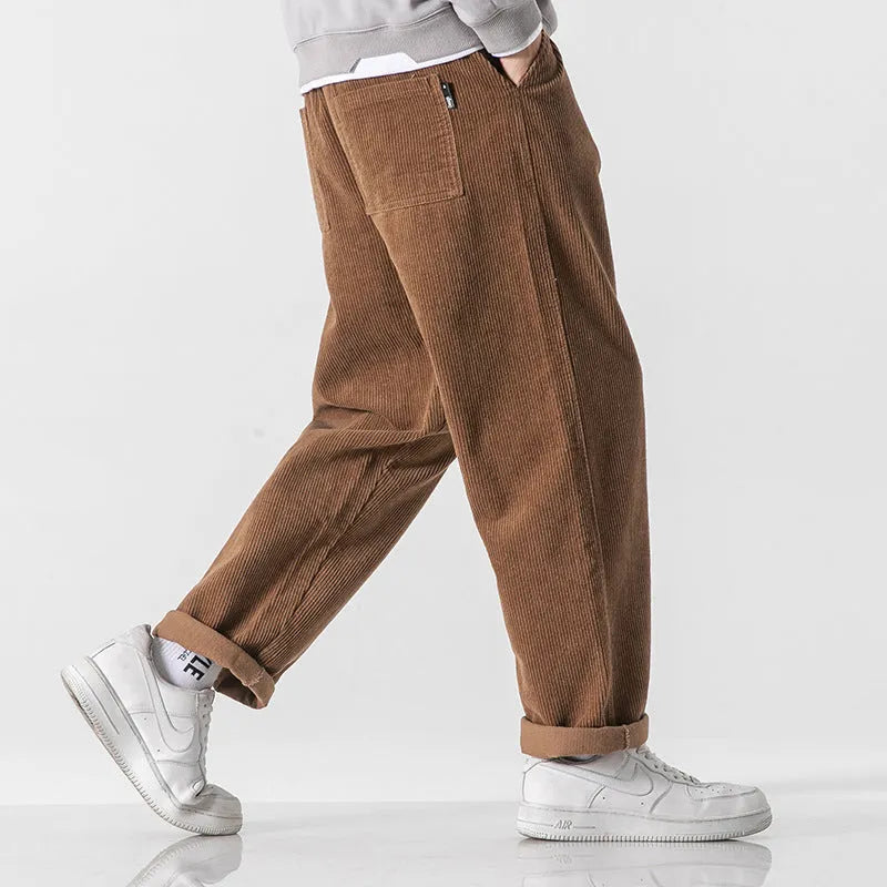 Men's loose straight corduroy sports trousers in black, front view, lying flat, showing waist and leg cut