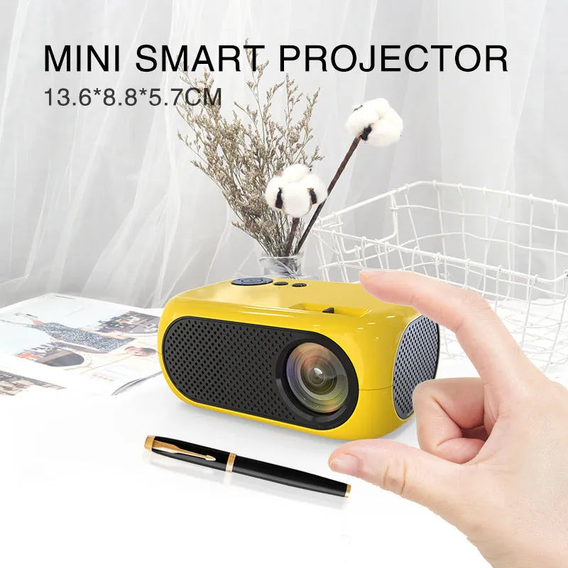 Compact gold and white M24 micro mini LED projector on a table with power adapter and AV cable.