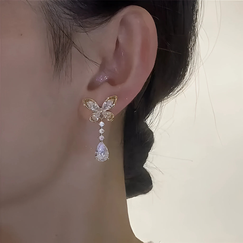 Pair of zinc alloy bow stud earrings with electroplated platinum finish on a white background