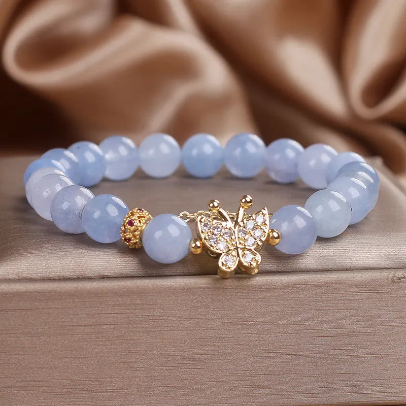 Sky blue crystal butterfly stretch bracelet for women with pearl and rhinestone accents on a plain background