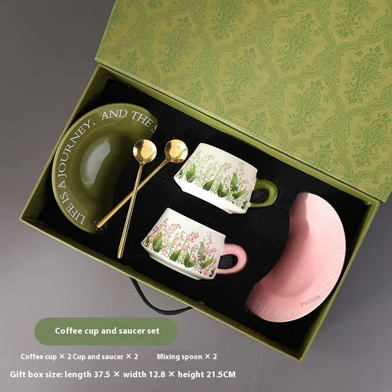 Ceramic coffee cup saucer set with two cups, two plates, and two spoons in matching design