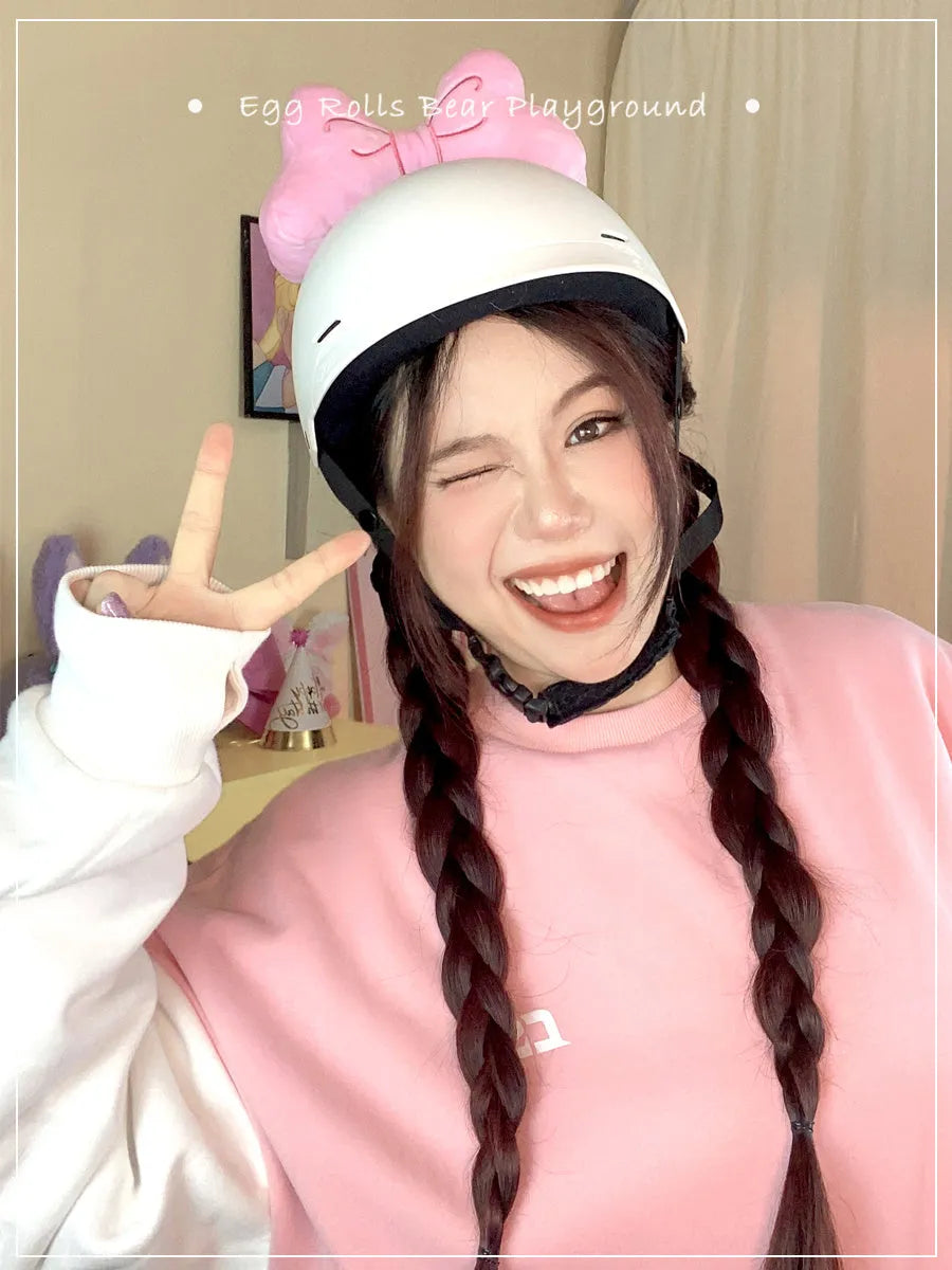 Plush bow tie helmet decoration in red, peach pink, and rose pink colours shown on a motorcycle helmet.