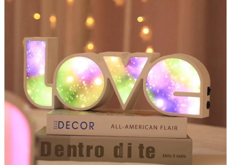 LED LOVE light with rainbow lampshade on a table against a dark background
