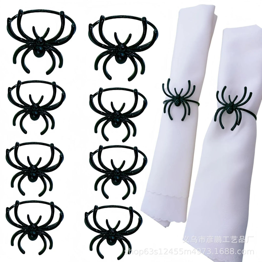 Six black alloy spider-shaped napkin rings for Halloween table decoration on a dark surface.