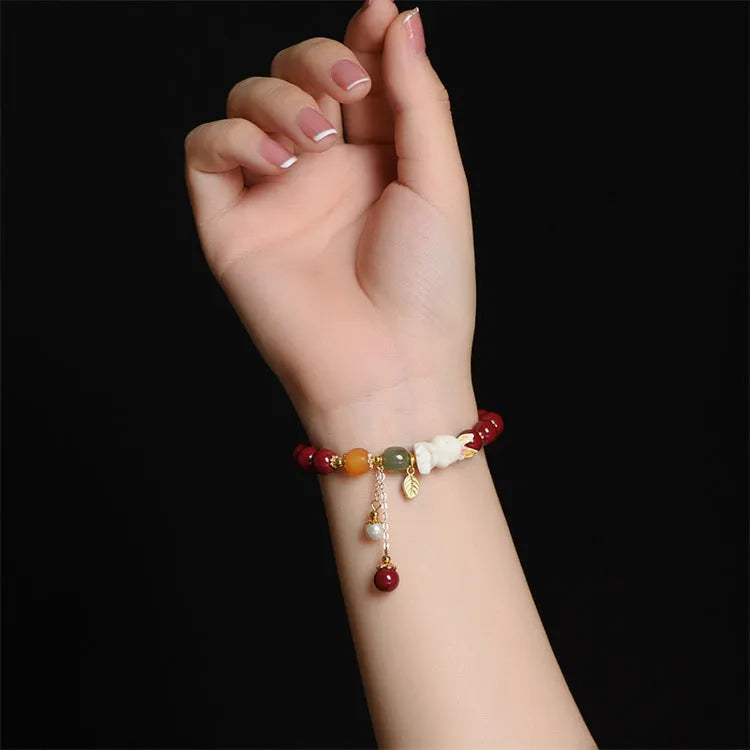 Women's bracelet with natural beeswax, purple gold sand beads, and a red cinnabar rabbit charm.