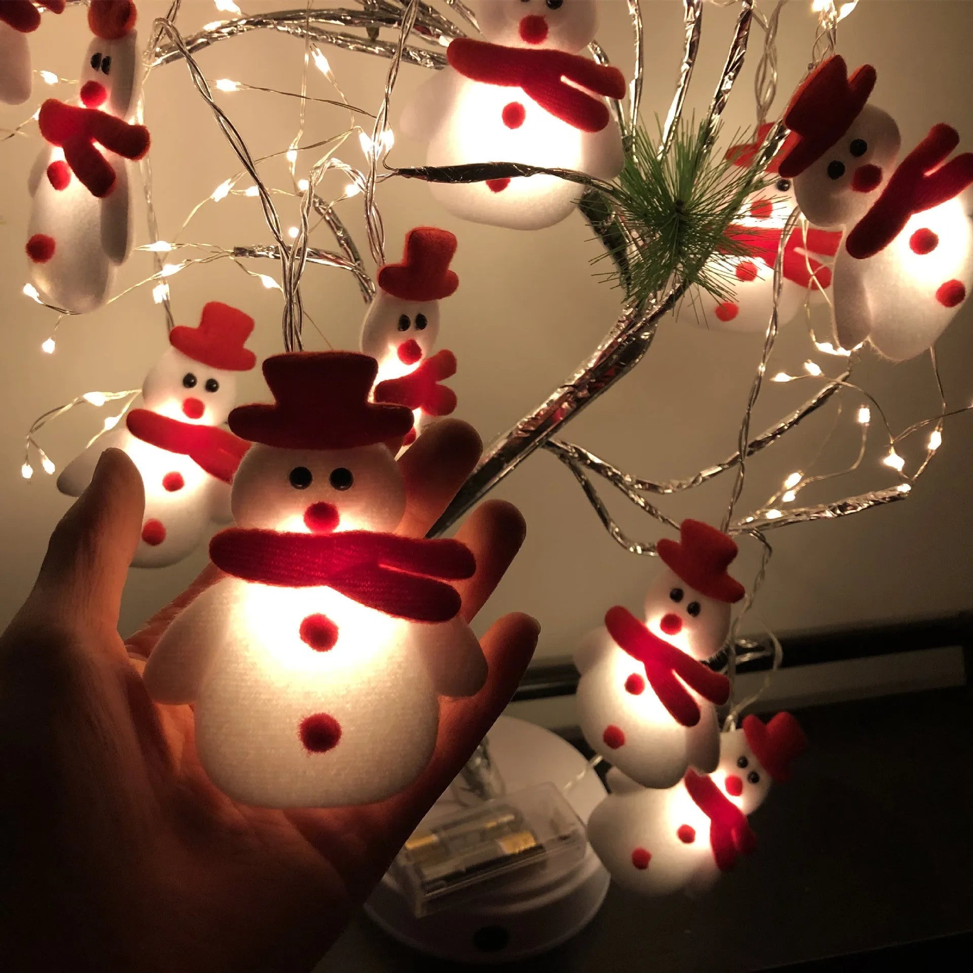 Snowman LED string lights garland with warm white glow on a Christmas tree