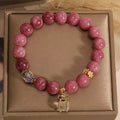 Natural stone beaded bracelet with pink lotus tassel, pearl pendant, and electroplated crystal beads on white background