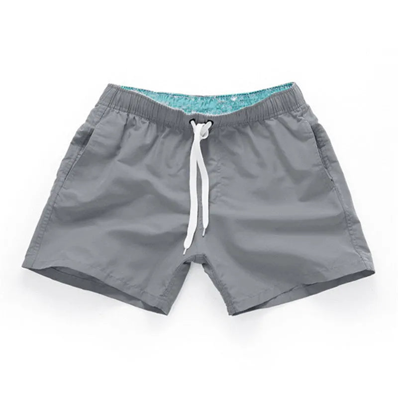 Men's straight-leg beach shorts in black polyester fabric on a size chart.