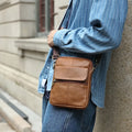 Men's brown genuine leather crossbody shoulder bag with sewing line details.
