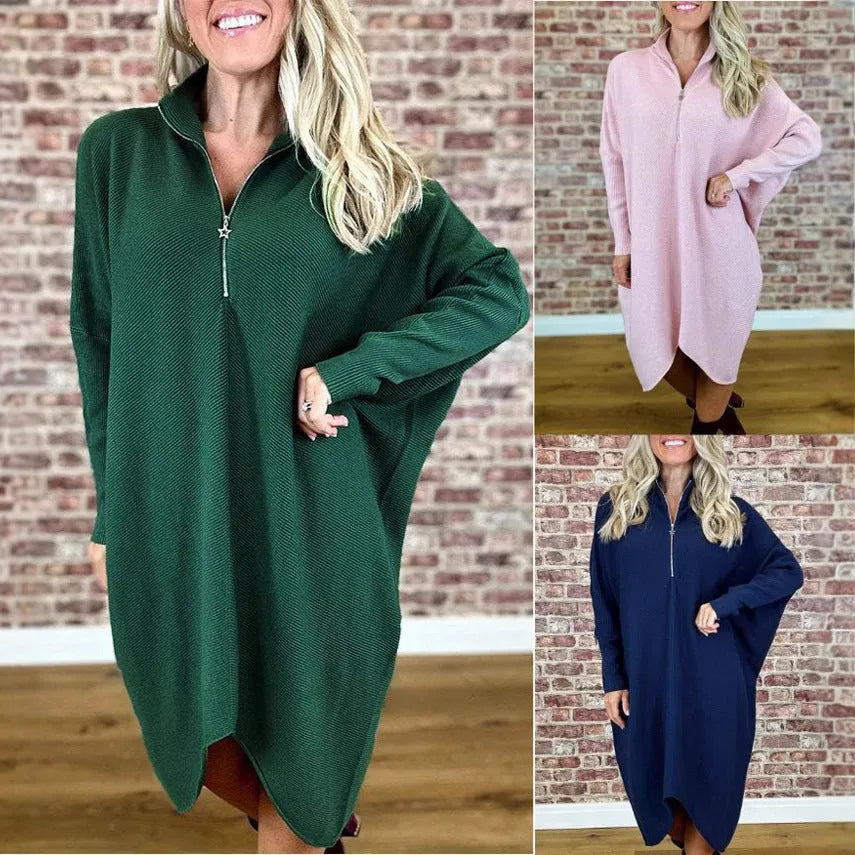 A woman modelling a loose-fitting dark green knitted dress with a front zipper detail and raglan sleeves.