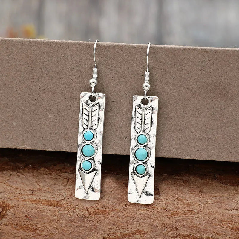 Long strip geometric silver earrings with inlaid turquoise detail on a white background