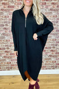 A woman modelling a loose-fitting dark green knitted dress with a front zipper detail and raglan sleeves.