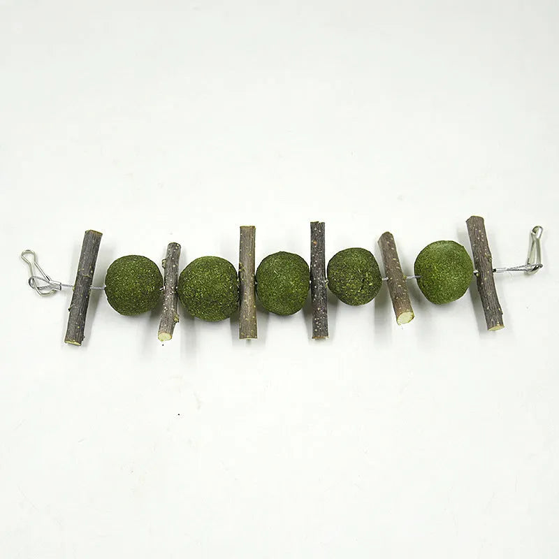 Natural pet molar supplies set with five grass balls and six apple branches hanging on a cage for small animals like rabbits and guinea pigs