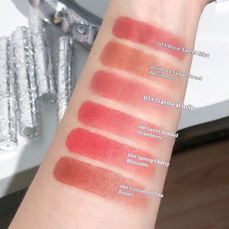 Velvet Mist Lip Mud matte white tube with six shade swatches: rose sweet mist, rock candy persimmon, oats cow's milk, sweet stained strawberries, spring cherry blossoms, cinnamon tea brown