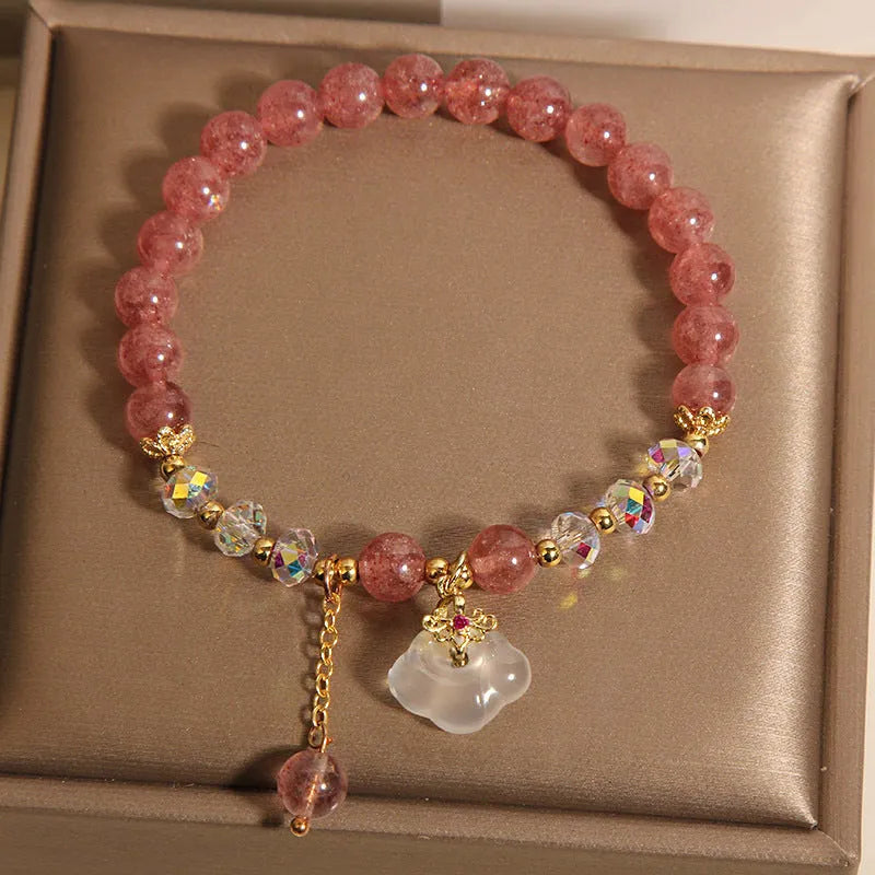 Women's natural strawberry quartz and white agate crystal bracelet with auspicious cloud pattern on a flat surface