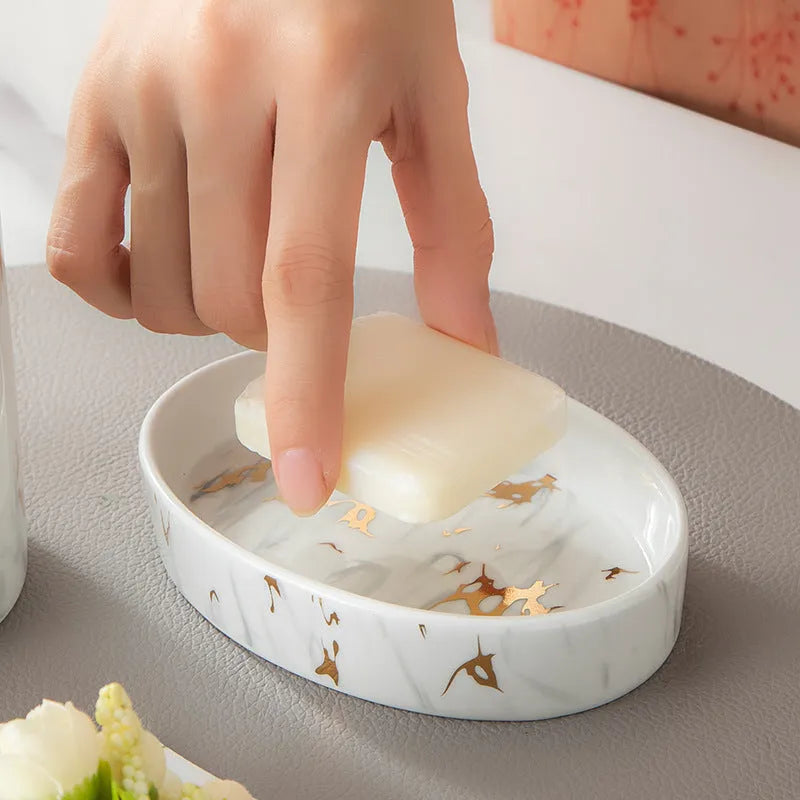 White marble ceramic bathroom wash kit with two cups, latex bottle, and soap box on a counter