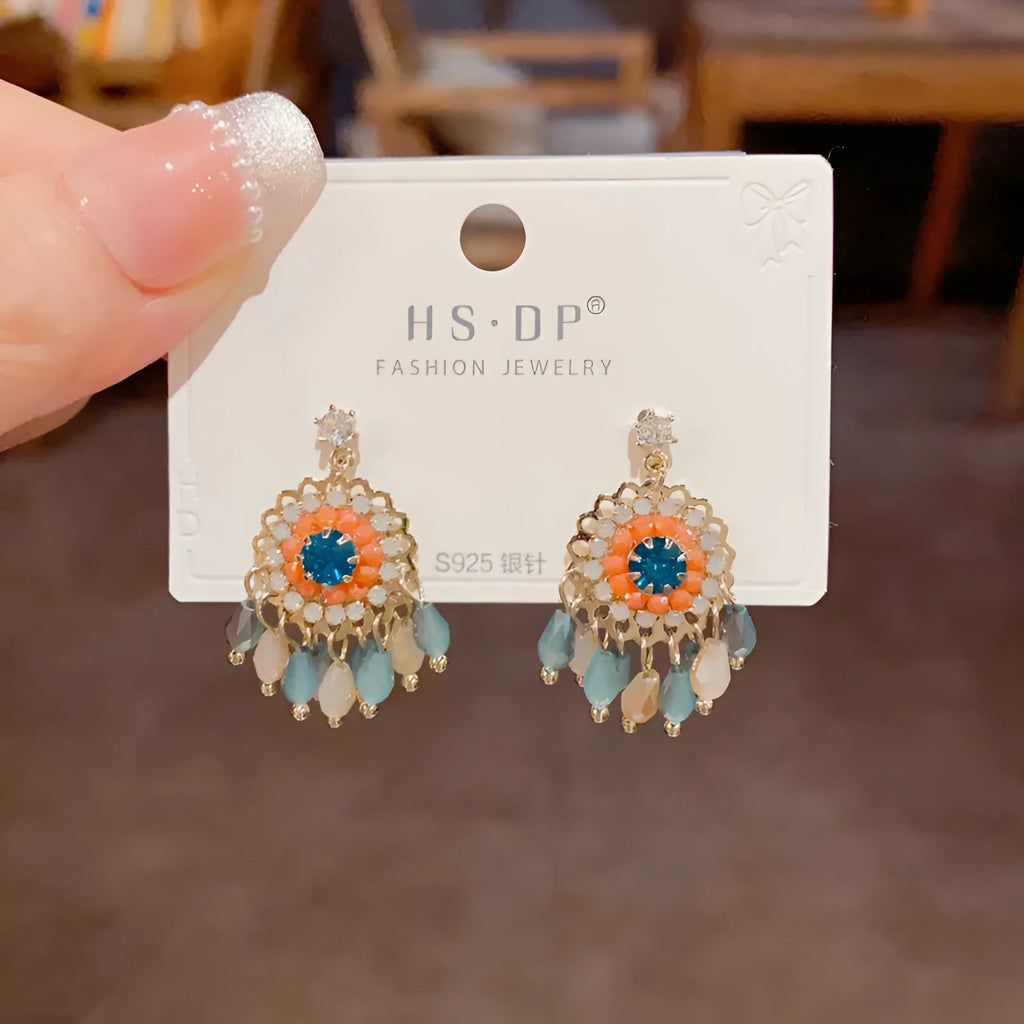 Pair of diamond embedded round crystal tassel earrings, thick gold plated, purple colour, on a white background