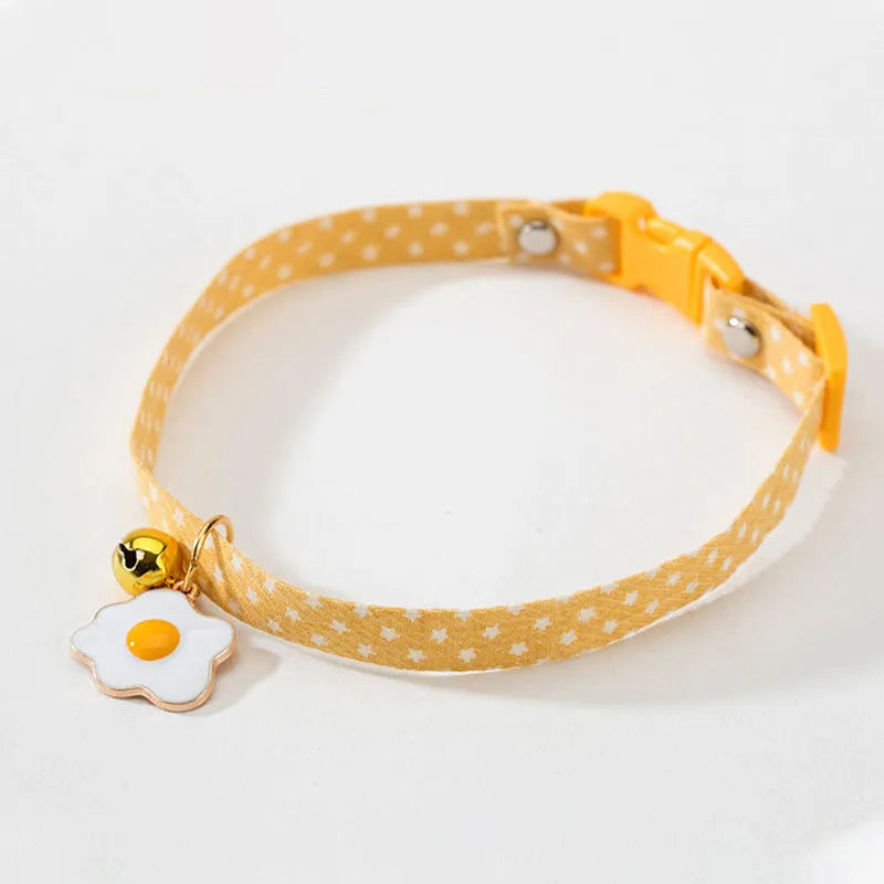 Green adjustable cat collar with a metal bell and red bow tie on a white background.
