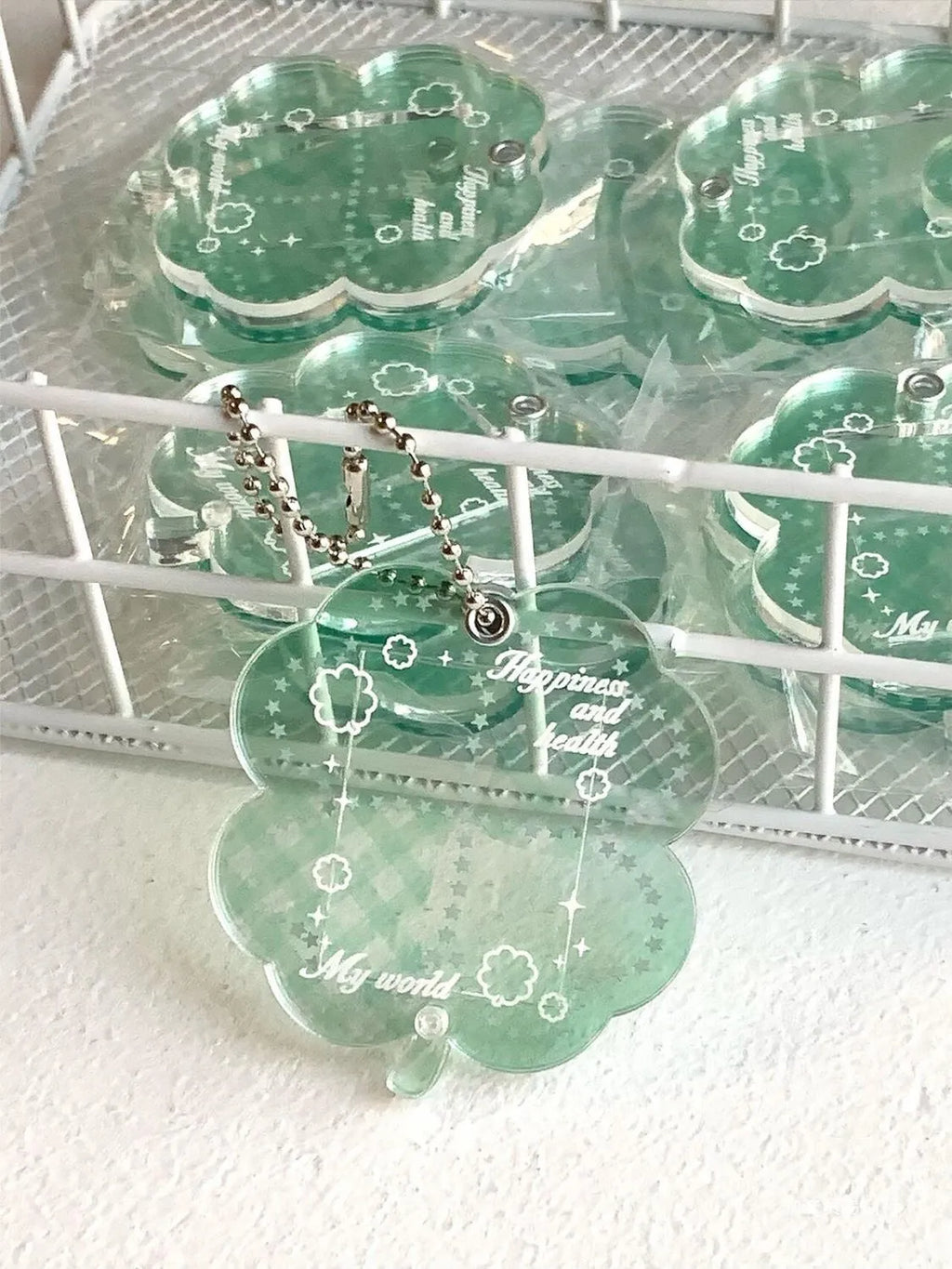 Four-leaf clover shaped acrylic pendant keychain in mint green colour on a surface